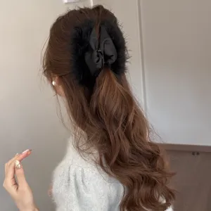 Detail shot of elegant black plush feather hair claw clip, versatile chic hair accessory for women.