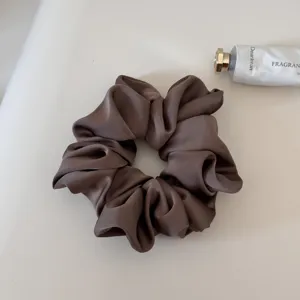 Detailed shot of a sleek brown satin scrunchie, elegant and smooth hair accessory.