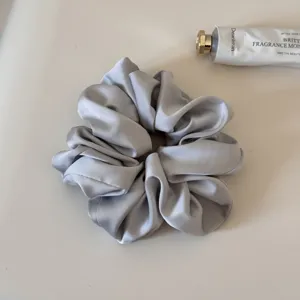 Detailed close-up shot of the elegant silver satin hair scrunchie with smooth soft texture.