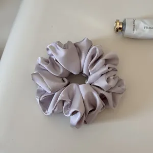 Elegant purple satin hair scrunchie, soft elastic ponytail holder for daily styling and hair care.