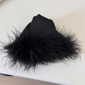 Black feather hair claw clip detail shot, elegant plush texture for charming hairstyles.
