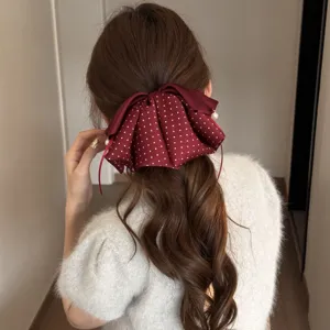 Nahaufnahme der bordeauxroten Polka-Dot-Haarschleife mit Perlen, elegante Rückansicht Frisur.