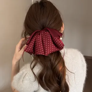Detailansicht einer burgunderroten Polka-Dot-Haarklammer mit feinem Perlenanhänger.