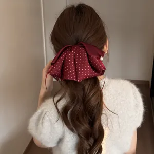 Detaillierte Nahaufnahme der eleganten Polka-Dot Schleifen-Haarklammer mit Perlendetail.