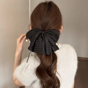 Detaillierte Ansicht einer schwarzen Perlen Haarklammer mit Punkten im braunen Haar, elegant.