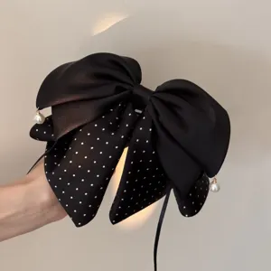 Schwarze Haarklammer mit Pünktchen, Schleife und Perlenanhängern, elegantes Haaraccessoire Detail.