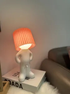 Detailed view of the funny little boy night light with pleated lampshade, placed on desktop.