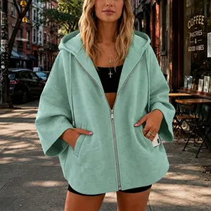 Detalle de chaqueta con capucha y cremallera verde menta, cómodo abrigo holgado manga 3/4.