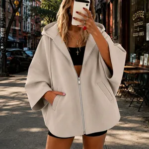 Vista detallada de la chaqueta beige con capucha y cremallera, mangas murciélago y bolsillos.