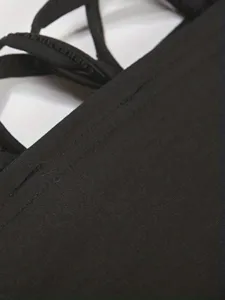 Detailed view of the black strappy dress, featuring fine stitching and cross design.