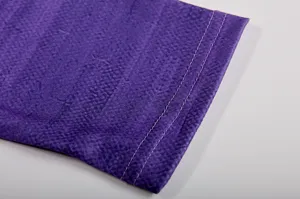 Purple long sleeve top cuff detail, fine textured fabric close-up view showing stitching.