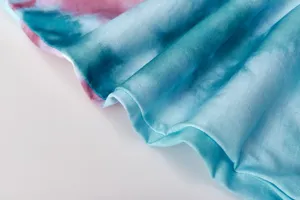 Close-up detail of soft tie-dye fabric featuring vibrant blue and pink gradient colors.