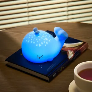 Vue détaillée de la jolie veilleuse baleine en silicone brillant chaleureusement sur un bureau.