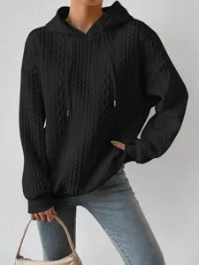 Detailed view of the black cable-knit hoodie with drawstring hood and cozy loose fit.