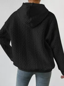 Detail view of a black knitted hooded sweatshirt featuring a textured pattern, cozy design.