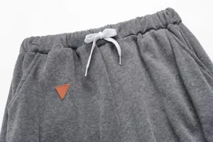 Grey fleece sweatpants detail featuring elastic waistband, white drawstring and leather patch.