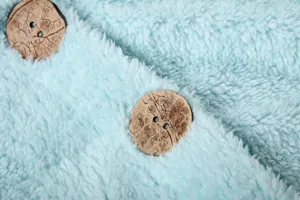 Detailed close-up of light blue plush fleece fabric featuring distinctive wooden buttons.