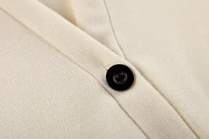 Gros plan détaillé d'un gilet en tricot beige doux avec col en V et fermeture à boutons.