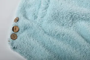 Detail shot of soft light blue plush fleece fabric featuring vintage wooden buttons texture.