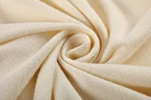 Détail de tissu en tricot beige gros plan montrant une texture douce et un motif de laine.