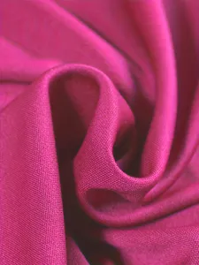 Primo piano di tessuto strutturato rosa liscio con pieghe eleganti e trama fine.