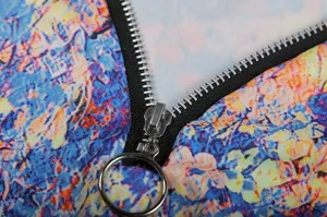 Close-up detail of women's floral printed top with metal ring zipper and vibrant fabric texture.
