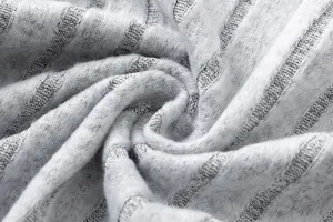 Detailed view of grey ribbed knitted fabric, soft and cozy texture for autumn fashion apparel.