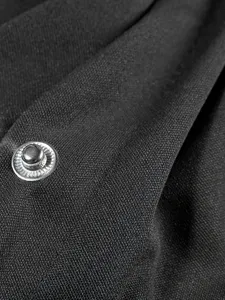 Close-up detail of black jacket fabric showing the texture and metallic snap button.
