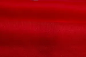 Detailaufnahme der weichen roten Strickstofftextur, die feine Handwerkskunst zeigt.