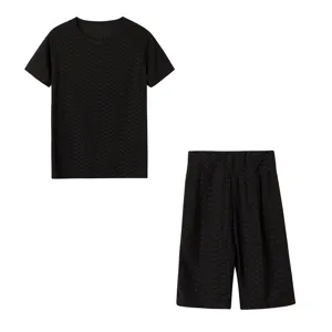 Dettaglio top a maniche corte strutturato a nido d'ape nero e pantaloncini tuta sportiva.