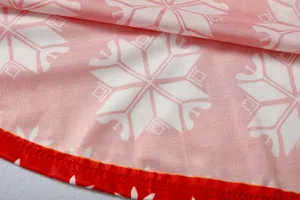 Close-up detail van de kerst sneeuwvlok print jurk stof met rode gestikte zoom rand.