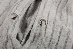 Grey ribbed knit hoodie detail close up featuring metal eyelets and adjustable drawstring.