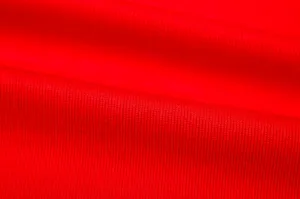 Close-up detail shot of vibrant red knitted fabric, showing fine texture and soft touch.