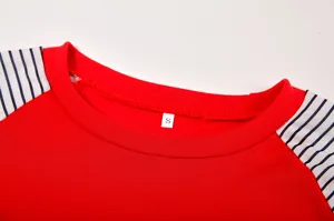 Detailed view of women's red crewneck long sleeve t-shirt with black and white striped sleeves.