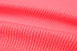 Close-up detail of soft coral pink knitted fabric texture, showing fine and clear knit patterns.