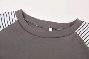 Close-up detail of women's crewneck long sleeve t-shirt with grey body and striped sleeves.