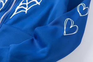 Gros plan sur le sweat à capuche bleu doublé de polaire, toile d'araignée et cœur.