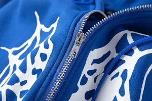 Gros plan sur les détails du sweat à capuche zippé en molleton à motif toile d'araignée.