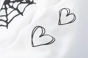 Gros plan détaillé d'un sweat à capuche blanc en molleton avec des imprimés de toile d'araignée.