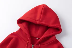 Détail de sweat à capuche zippé rouge, doublure polaire douce et cordon de serrage ajustable.