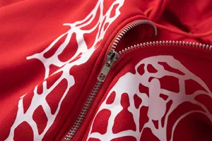 Vue détaillée du sweat à capuche rouge avec imprimé toile d'araignée blanche et fermeture.