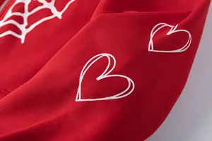 Vue détaillée du sweat à capuche zippé en molleton rouge avec motifs toile et cœurs.