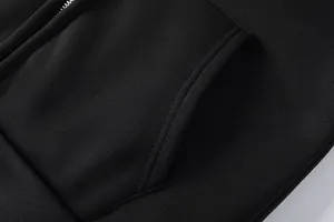 Détail de poche de sweat à capuche en molleton noir, texture chaude et fermeture éclair.