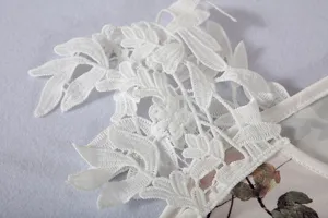 Close-up detail of white lace trim and floral print on women summer dress fabric.