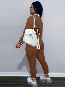 Dettaglio di tuta marrone con colletto a righe bianche per un look sportivo ed elegante.