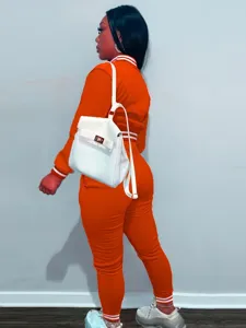 Vista dettagliata della tuta sportiva arancione da donna con giacca e pantaloni coordinati.
