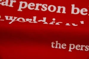 Close up of red fleece hoodie fabric with white letter print detail for women detail view.