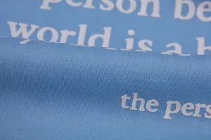 Detailed close up of light blue fleece sweatshirt fabric featuring white letter print.