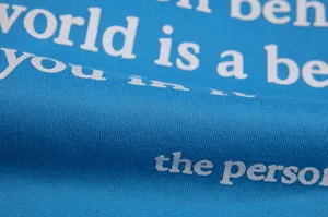 Close-up detail view of blue fleece sweatshirt fabric showing clear white letter print.