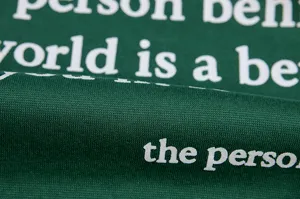 Dark green fleece sweatshirt fabric detail with white letter print showcasing textile texture.